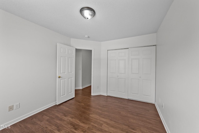 unfurnished bedroom featuring dark wood-style floors, a closet, and baseboards