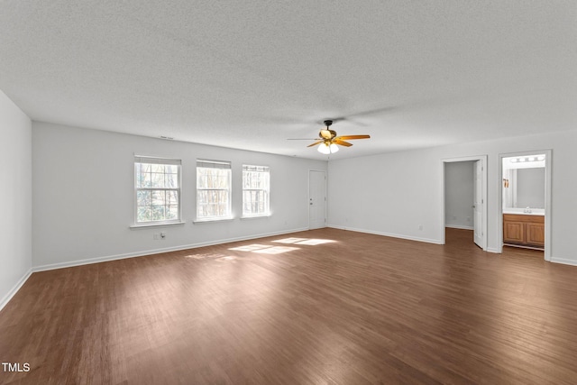 spare room with baseboards, ceiling fan, dark wood-style flooring, a textured ceiling, and a sink