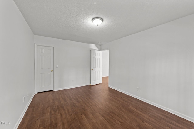 spare room featuring dark wood finished floors, a textured ceiling, and baseboards