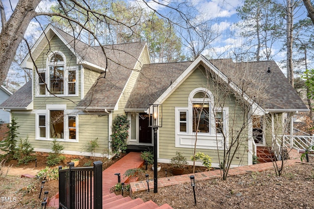 view of front facade featuring a shingled roof and fence