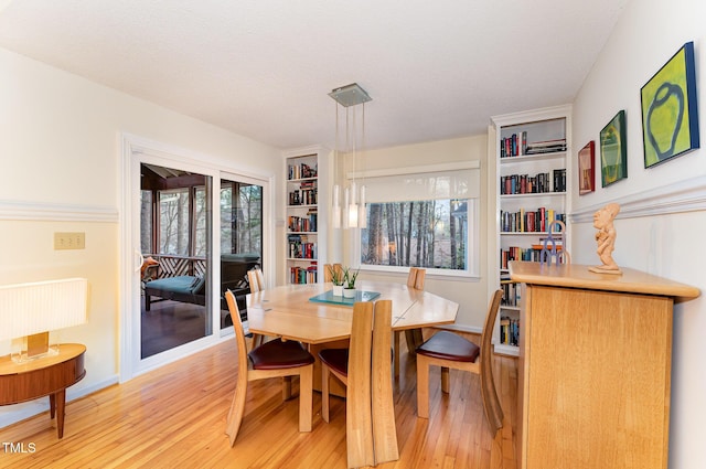 dining room with built in shelves, light wood-style flooring, and a textured ceiling