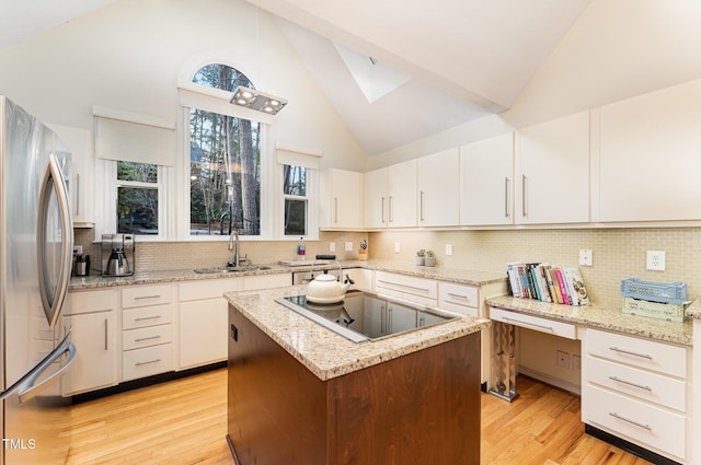 kitchen with black electric cooktop, a sink, white cabinetry, light wood-style floors, and freestanding refrigerator