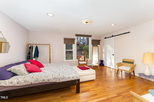 bedroom featuring light wood-style floors, a barn door, and recessed lighting