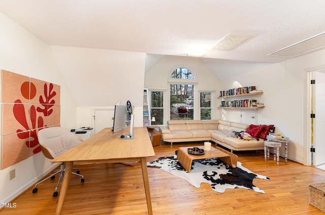 office area featuring light wood finished floors, baseboards, and vaulted ceiling