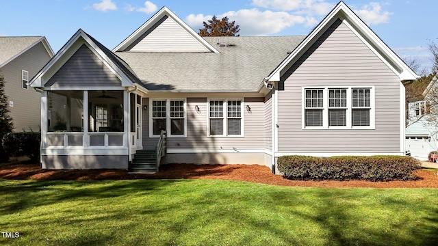 rear view of property featuring a shingled roof, a sunroom, and a lawn