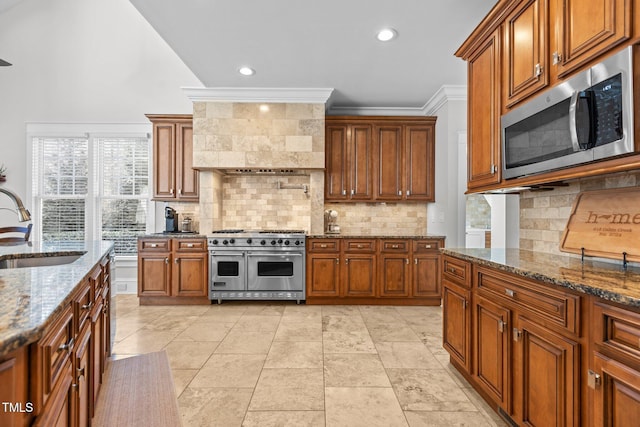 kitchen with dark stone counters, appliances with stainless steel finishes, a sink, and decorative backsplash