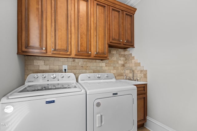 clothes washing area featuring washing machine and dryer, cabinet space, a sink, and baseboards