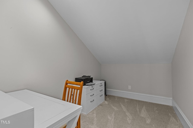 office area featuring light carpet, vaulted ceiling, and baseboards