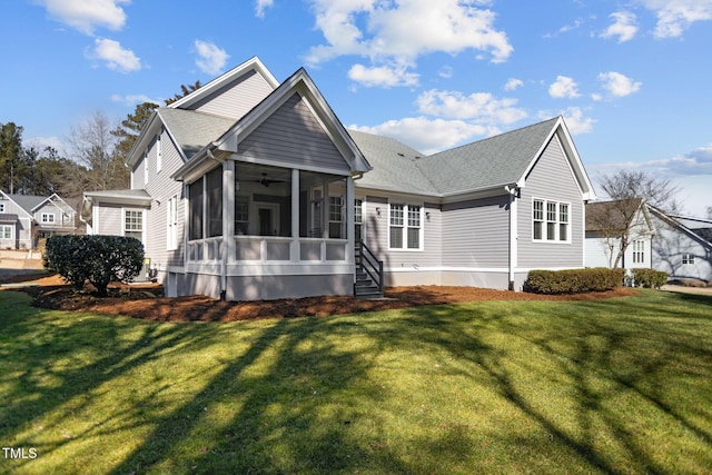 rear view of house with a shingled roof, a lawn, and a sunroom