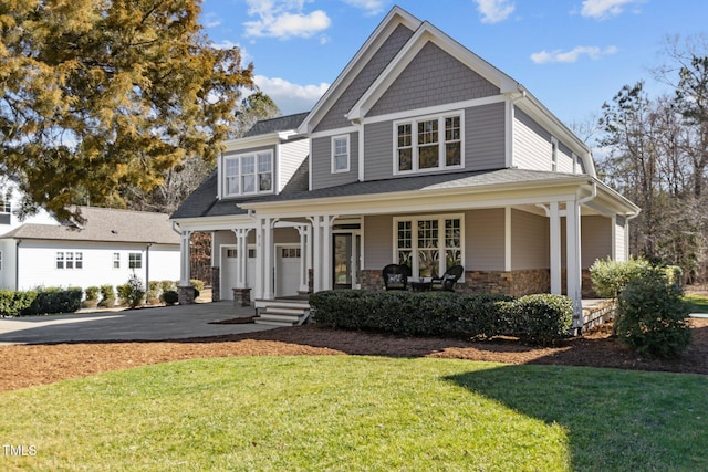 view of front of property with aphalt driveway, a porch, an attached garage, stone siding, and a front lawn