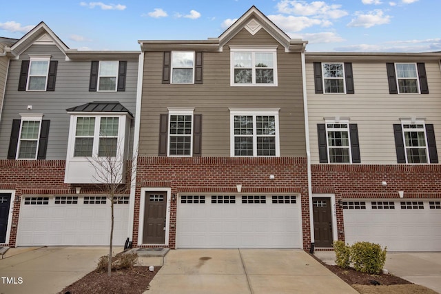 view of property featuring driveway, a garage, and brick siding