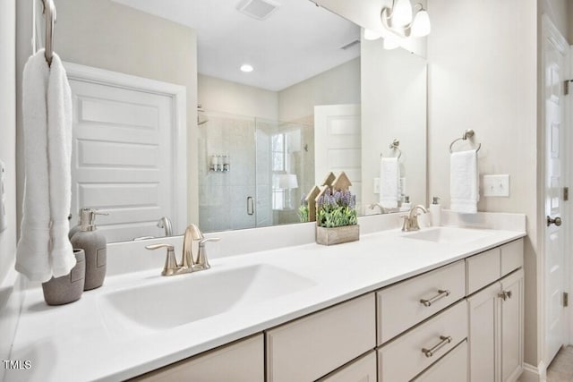 bathroom featuring double vanity, a stall shower, a sink, and visible vents