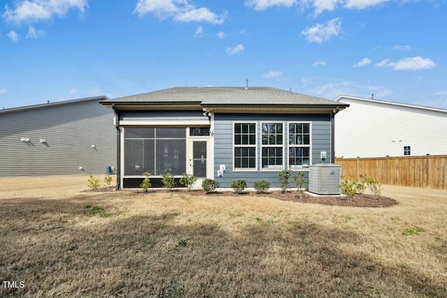 rear view of house with a yard, central AC unit, fence, and a sunroom