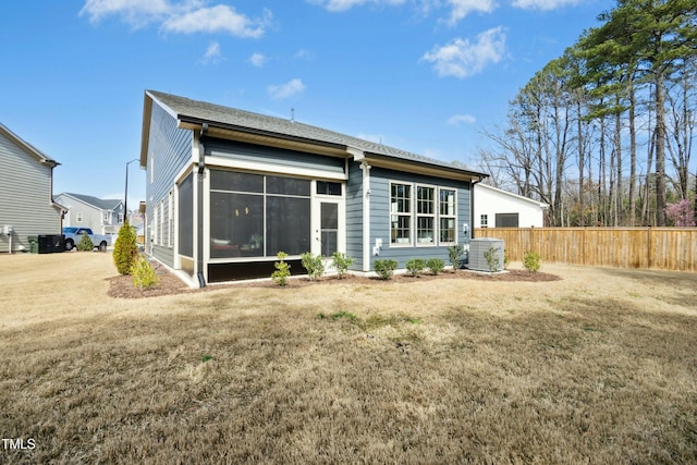 rear view of property with a sunroom, a lawn, fence, and cooling unit