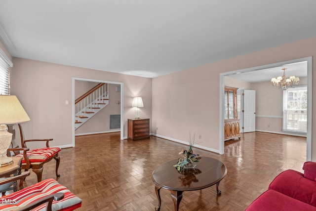 living area featuring visible vents, stairway, baseboards, and an inviting chandelier