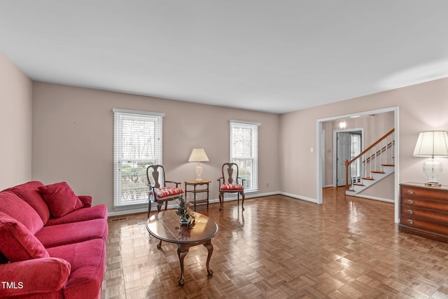 living area featuring baseboards and stairs