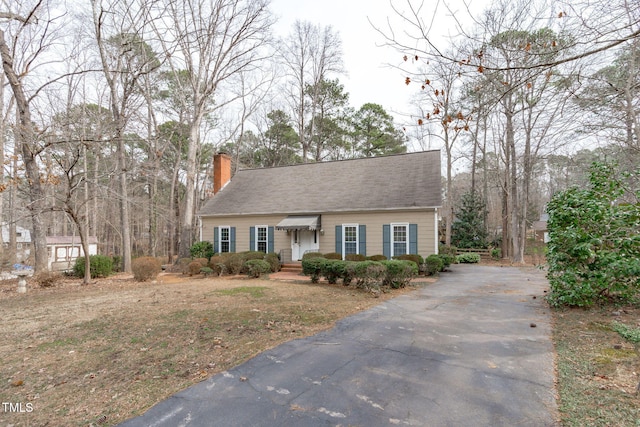 view of front of home featuring a chimney and aphalt driveway