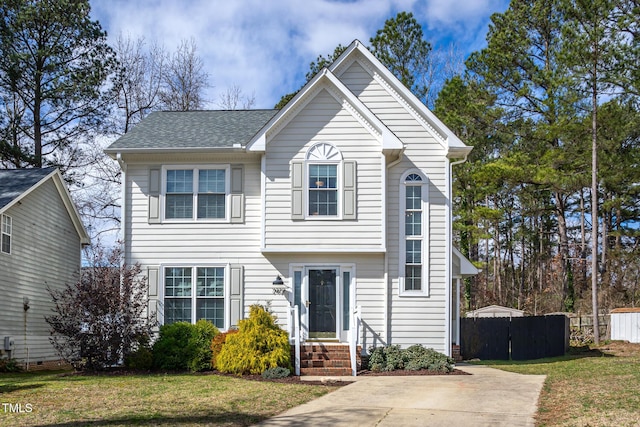 view of front of house featuring a shingled roof, fence, and a front yard