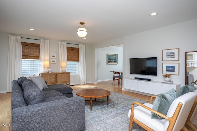 living area with baseboards, plenty of natural light, light wood-style flooring, and recessed lighting