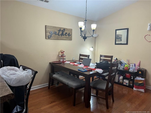 dining space with lofted ceiling, dark hardwood / wood-style floors, and an inviting chandelier