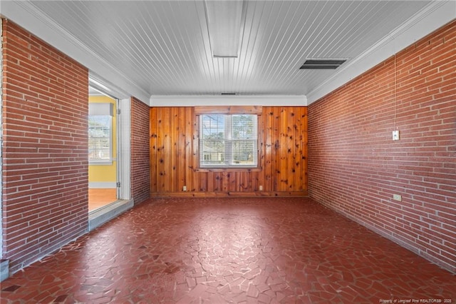 unfurnished room featuring ornamental molding and brick wall