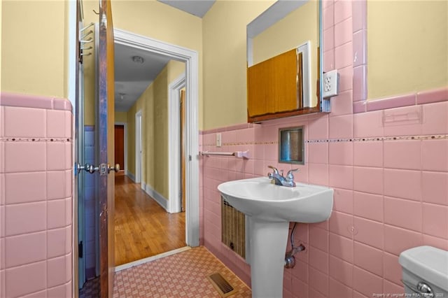 bathroom featuring sink, tile walls, and toilet