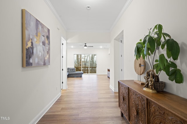 hall featuring ornamental molding, light wood-style flooring, and baseboards