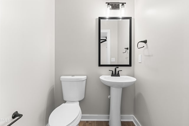 bathroom featuring a sink, baseboards, toilet, and wood finished floors