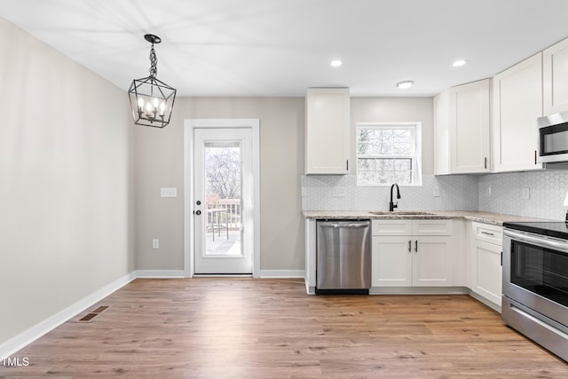 kitchen with visible vents, a sink, backsplash, white cabinetry, and appliances with stainless steel finishes