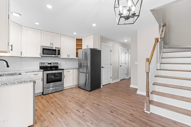 kitchen featuring white cabinetry, stainless steel appliances, light wood-type flooring, and a sink