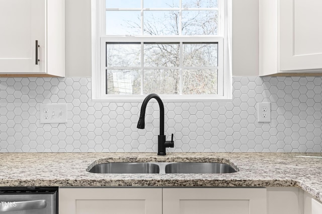 room details featuring light stone countertops, white cabinetry, a sink, decorative backsplash, and dishwasher