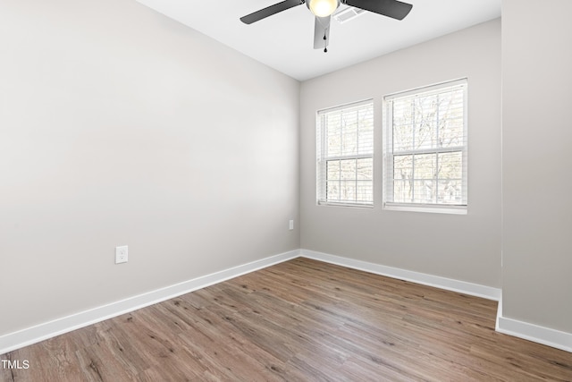 spare room with visible vents, a ceiling fan, baseboards, and wood finished floors