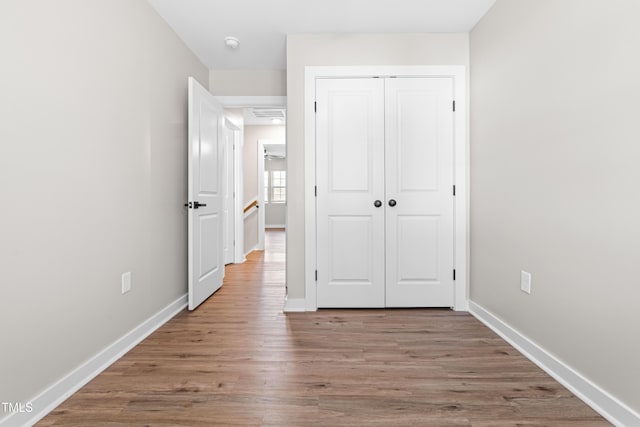 unfurnished bedroom with wood finished floors, baseboards, and a closet