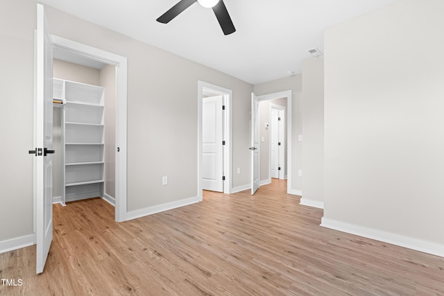 unfurnished bedroom with visible vents, a spacious closet, baseboards, and light wood-type flooring