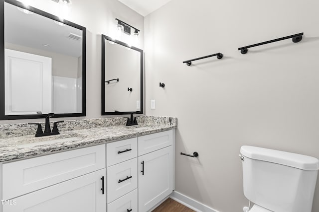 bathroom with visible vents, toilet, baseboards, and a sink