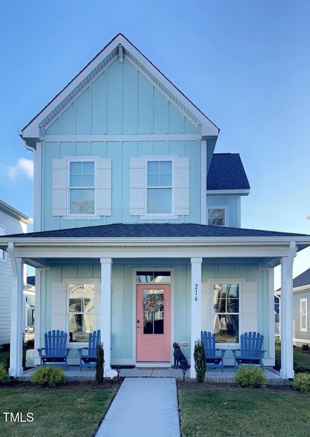 view of front facade with board and batten siding, a front lawn, a porch, and a shingled roof