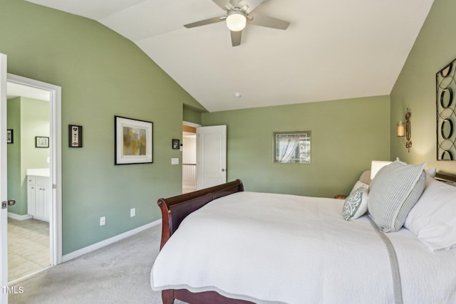 bedroom featuring light colored carpet, ensuite bathroom, a ceiling fan, vaulted ceiling, and baseboards