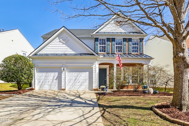 traditional-style house with metal roof, a porch, a garage, driveway, and a standing seam roof