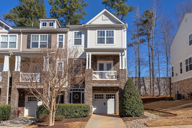 view of property featuring concrete driveway, stone siding, central AC unit, and an attached garage