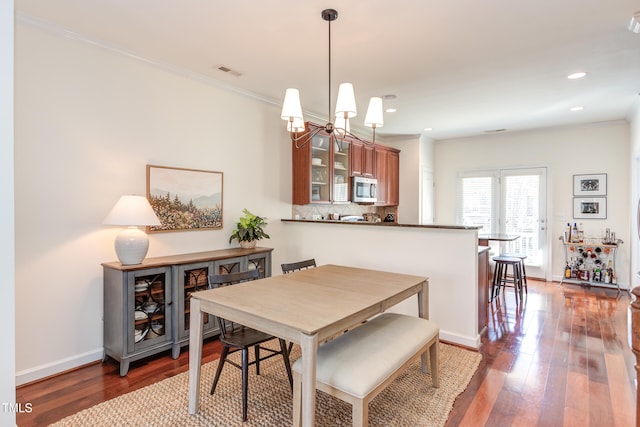 dining space with dark wood-type flooring, visible vents, and crown molding