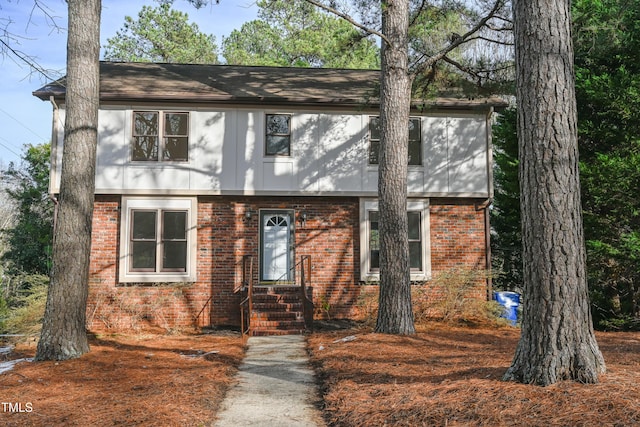 colonial-style house featuring entry steps and brick siding