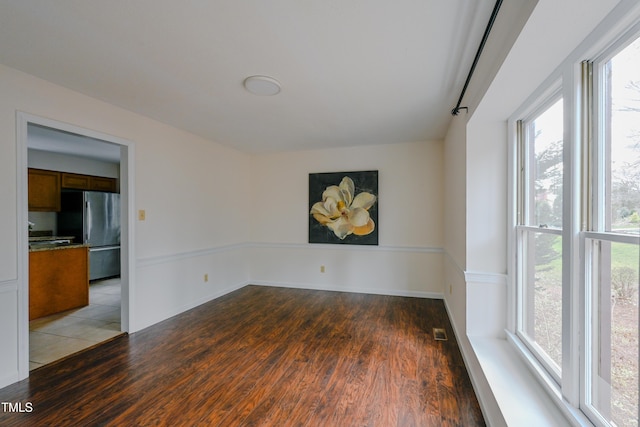 spare room with baseboards, visible vents, and wood finished floors