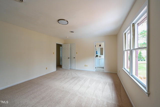 spare room with light carpet, visible vents, and baseboards