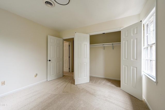 unfurnished bedroom featuring light colored carpet, a closet, visible vents, and baseboards