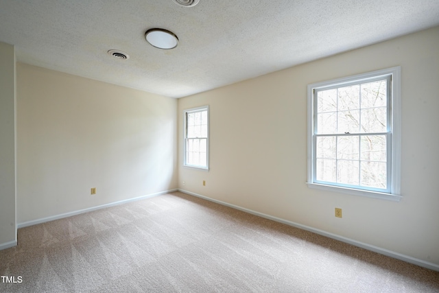 empty room with baseboards, a textured ceiling, visible vents, and carpet flooring