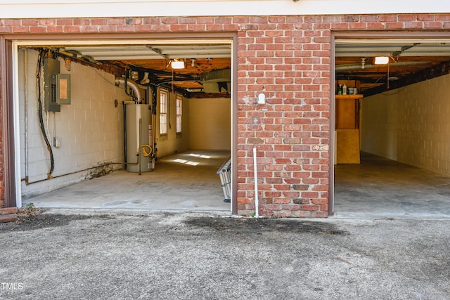 below grade area with concrete block wall, electric panel, and gas water heater