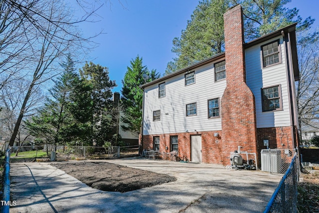 rear view of property with brick siding, fence, and central AC