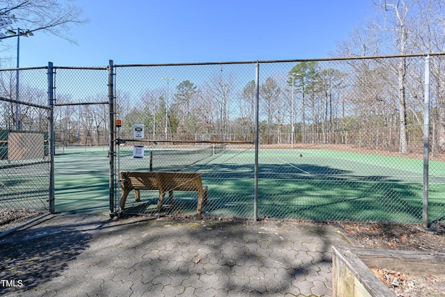 view of tennis court with a gate and fence