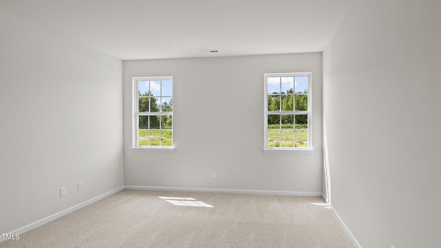 unfurnished room featuring light carpet and baseboards