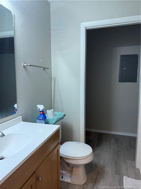 bathroom with toilet, vanity, electric panel, and wood-type flooring